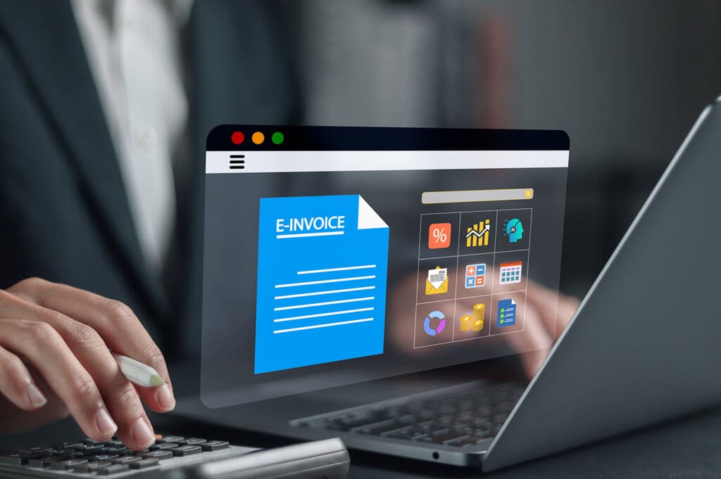 Businessperson using laptop with a digital screen displaying an e-invoice and financial management icons.