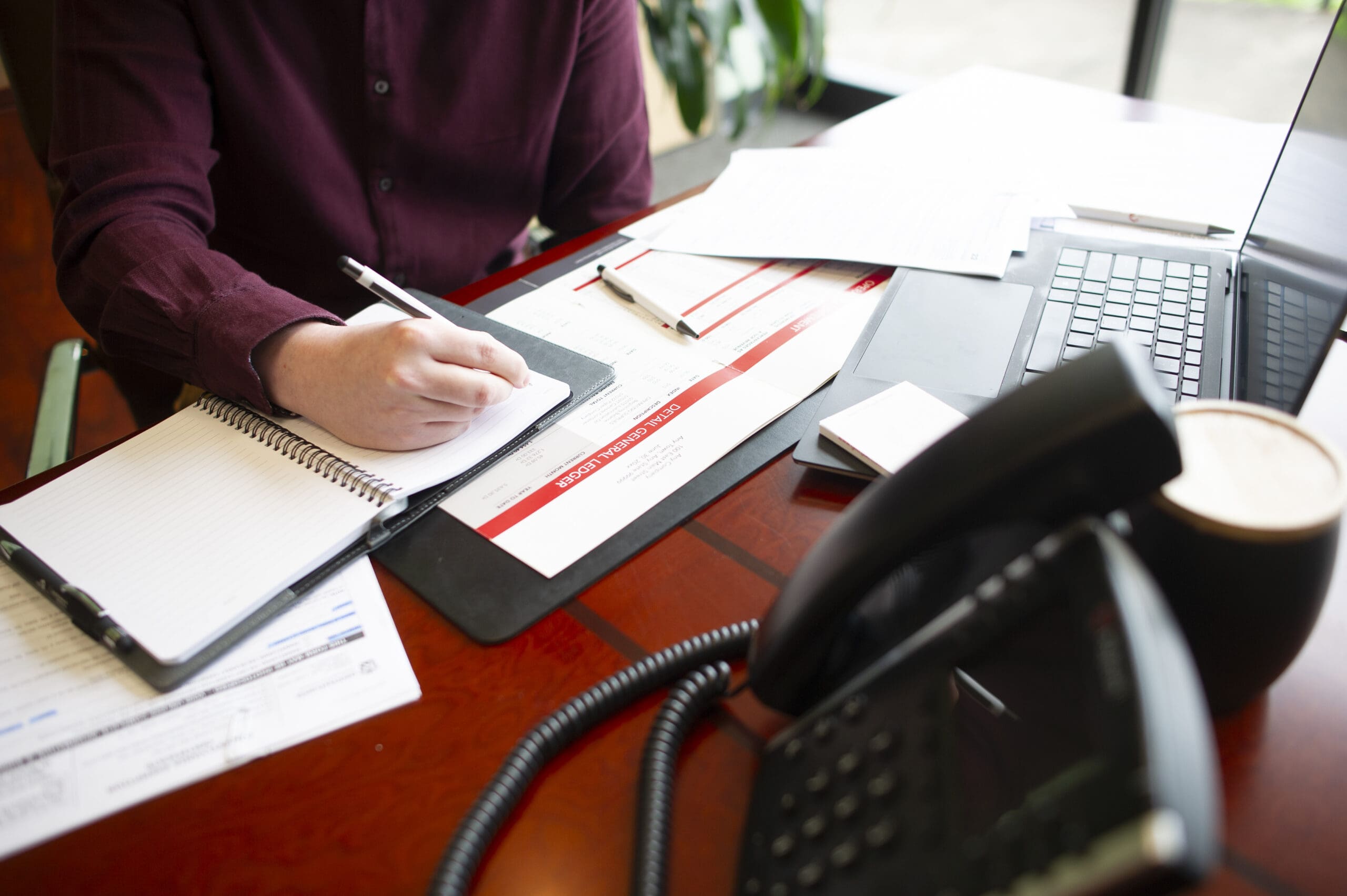 A person sitting at a desk, looking over accounting paperwork.