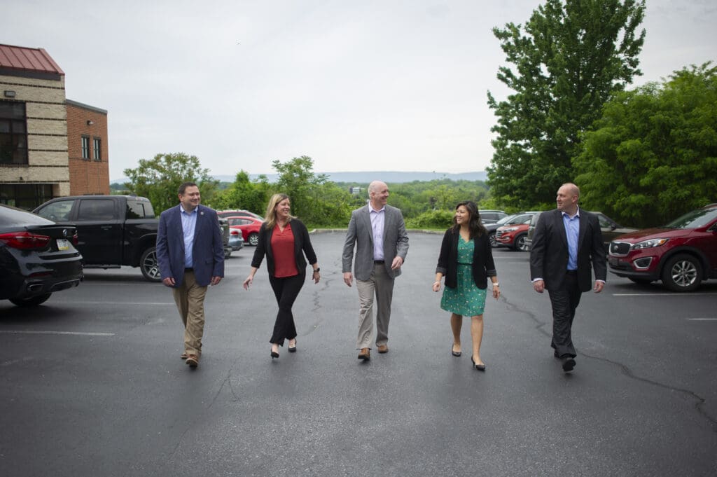 A group of GiftCPAs employees walking in a parking lot towards the camera, all smiling at each other.