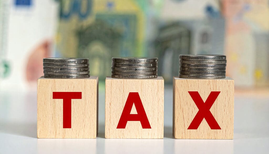 Coins stacked over letter blocks that say tax.