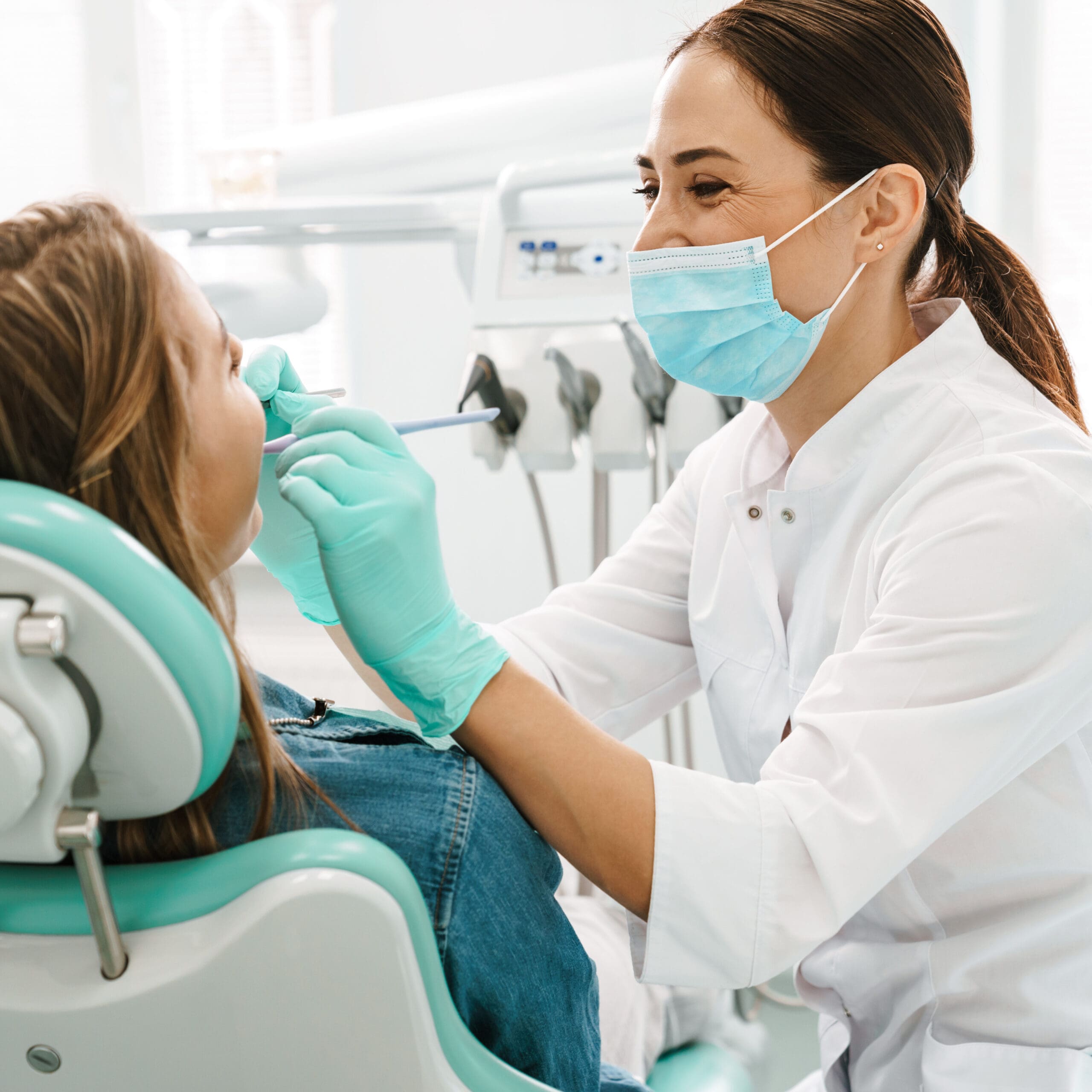 happy dentist in face mask working on patient