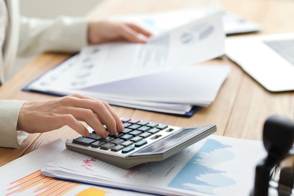 Female accountant working with calculator and documents at table in office.
