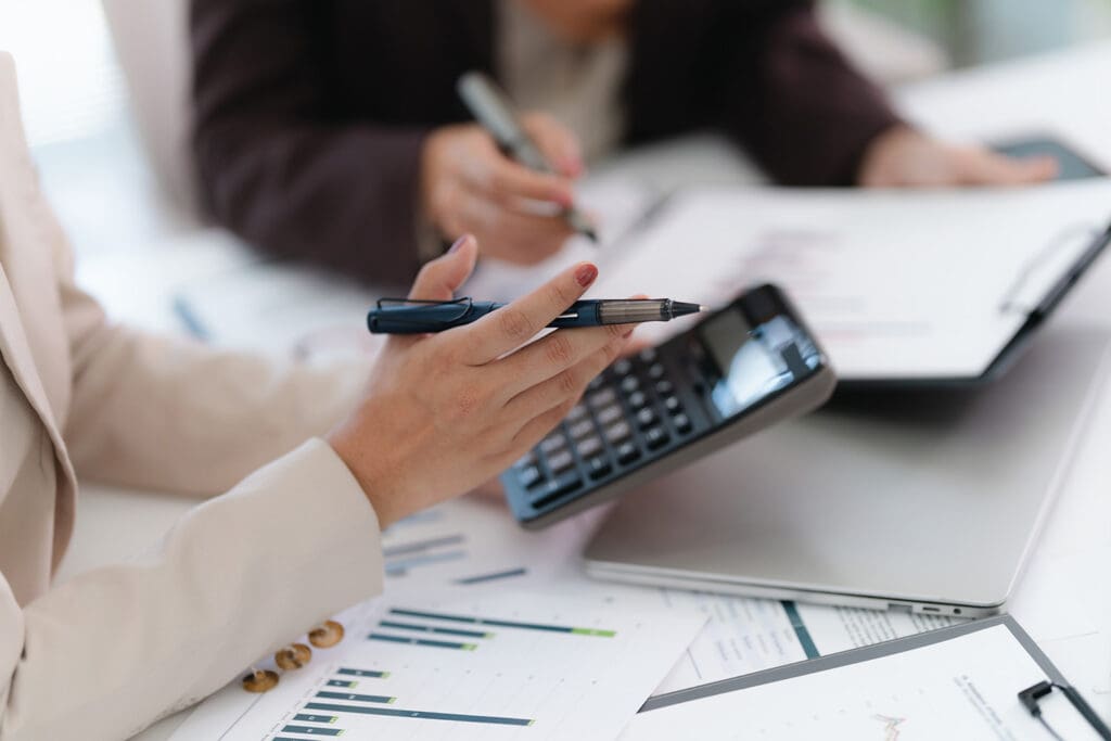 A woman holding a calculator and pen while reviewing financial statements.
